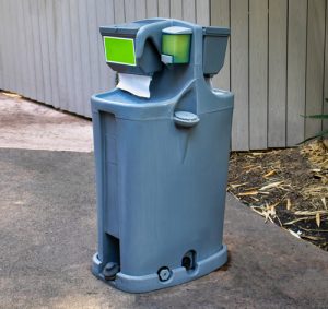 portable hand washing station next to a shed on concrete